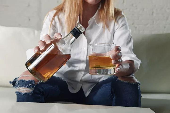 Alkohlsüchtige mit Flasche auf dem Bett