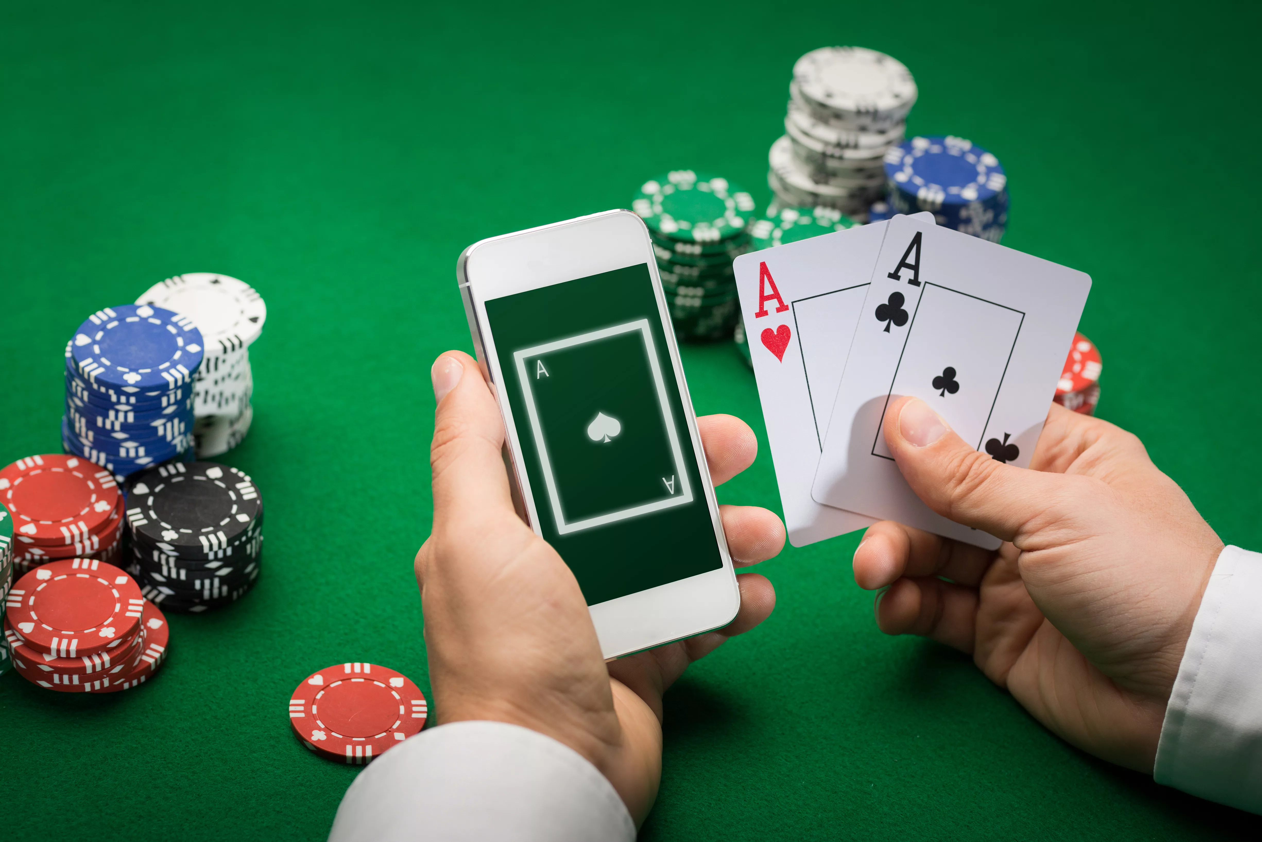 Mann mit Smartphone und Pokerkarten